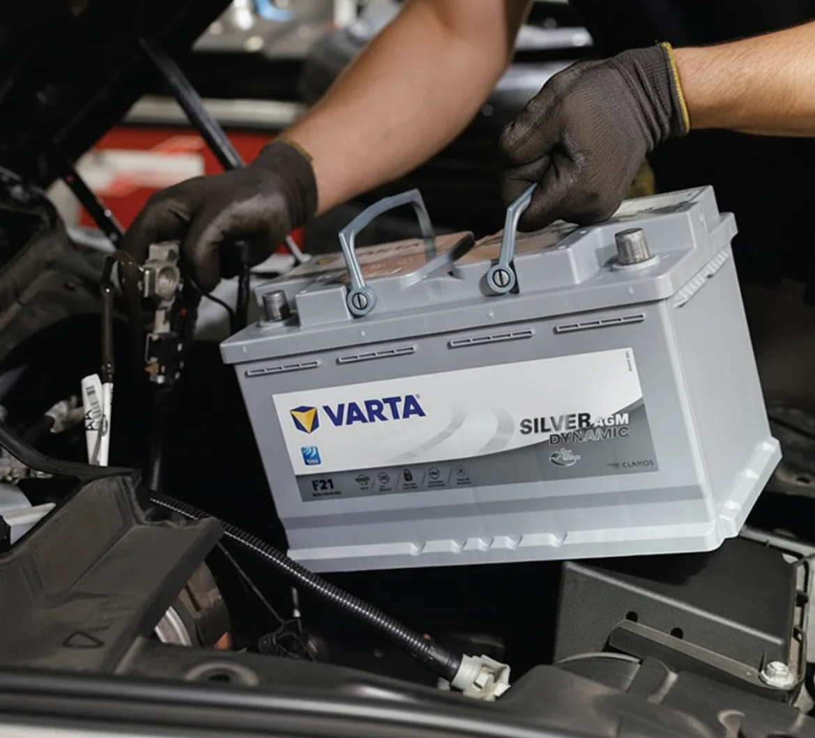 Black-gloved hands lifting a Varta Silver battery into a car's engine bay
