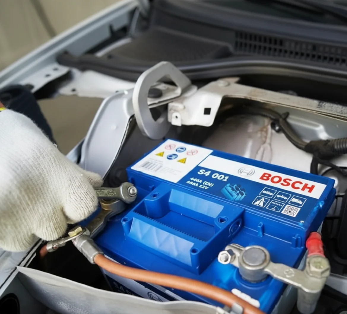 A gloved hand disconnecting the cable from the terminal of a Bosch S4 battery