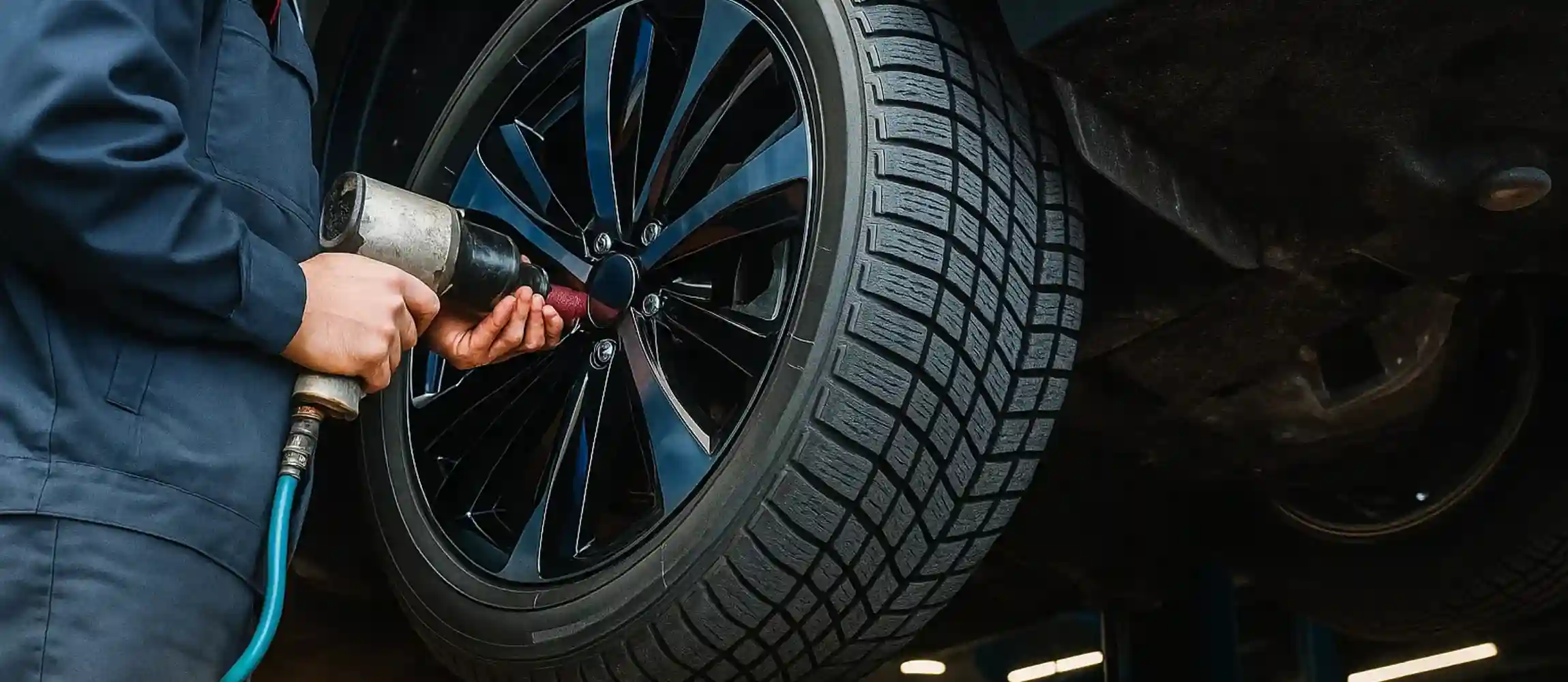 Technician running an impact wrench on the wheel nuts of an alloy wheel
